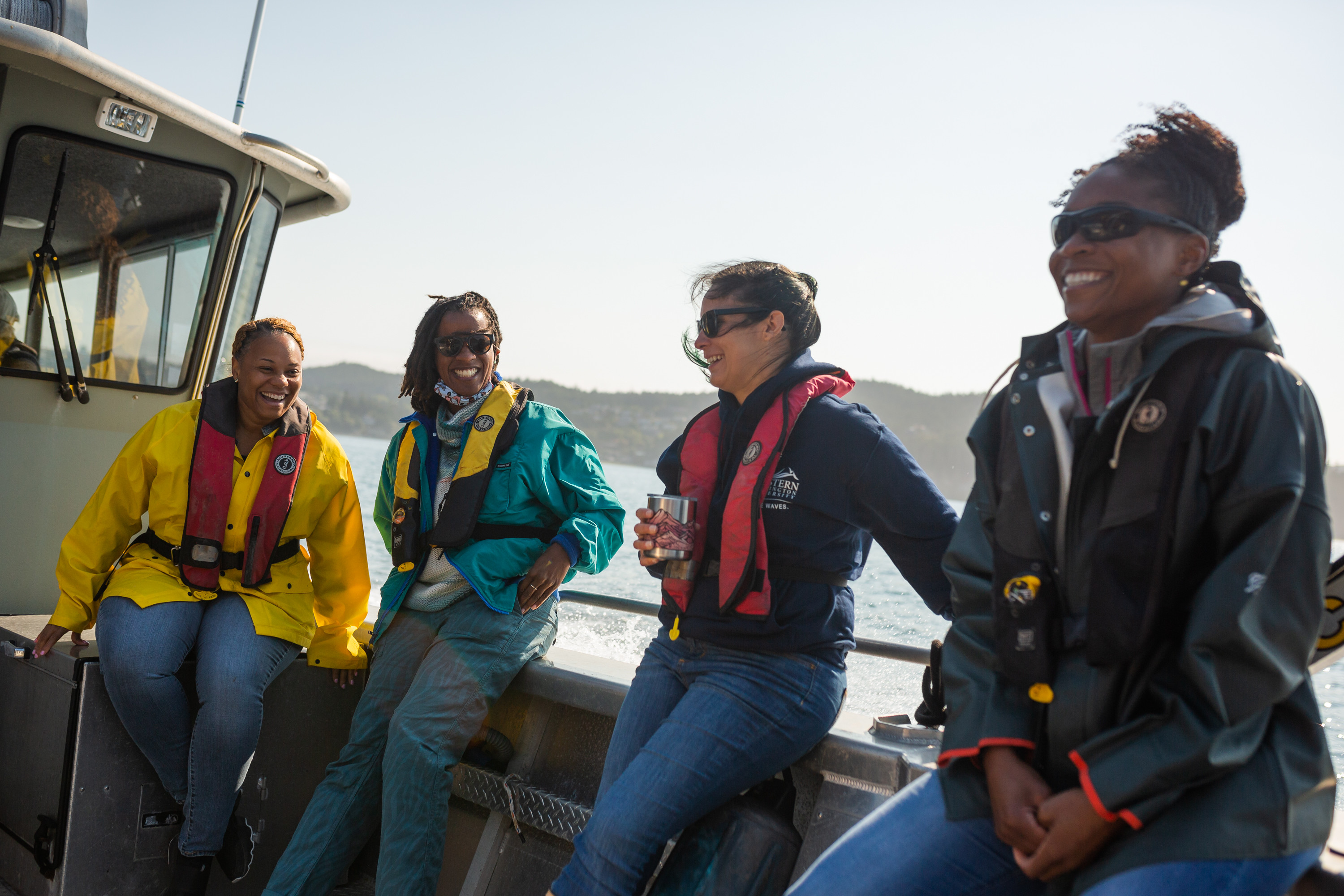 Group of students in life jackets enjoying the sunshine during a boat ride on the salish sea.