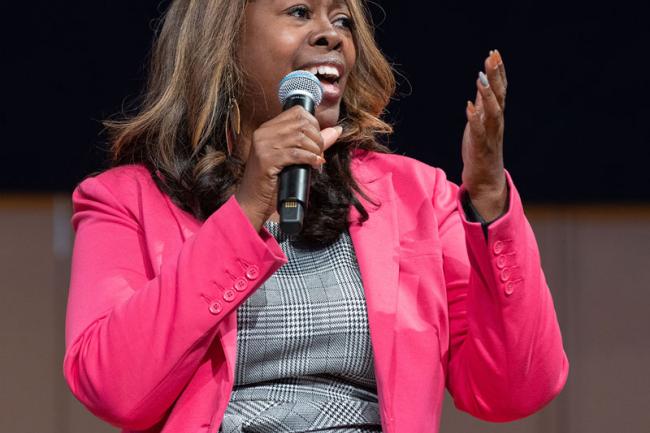 Latosha Brown in a pink jacket, speaking into a microphone.